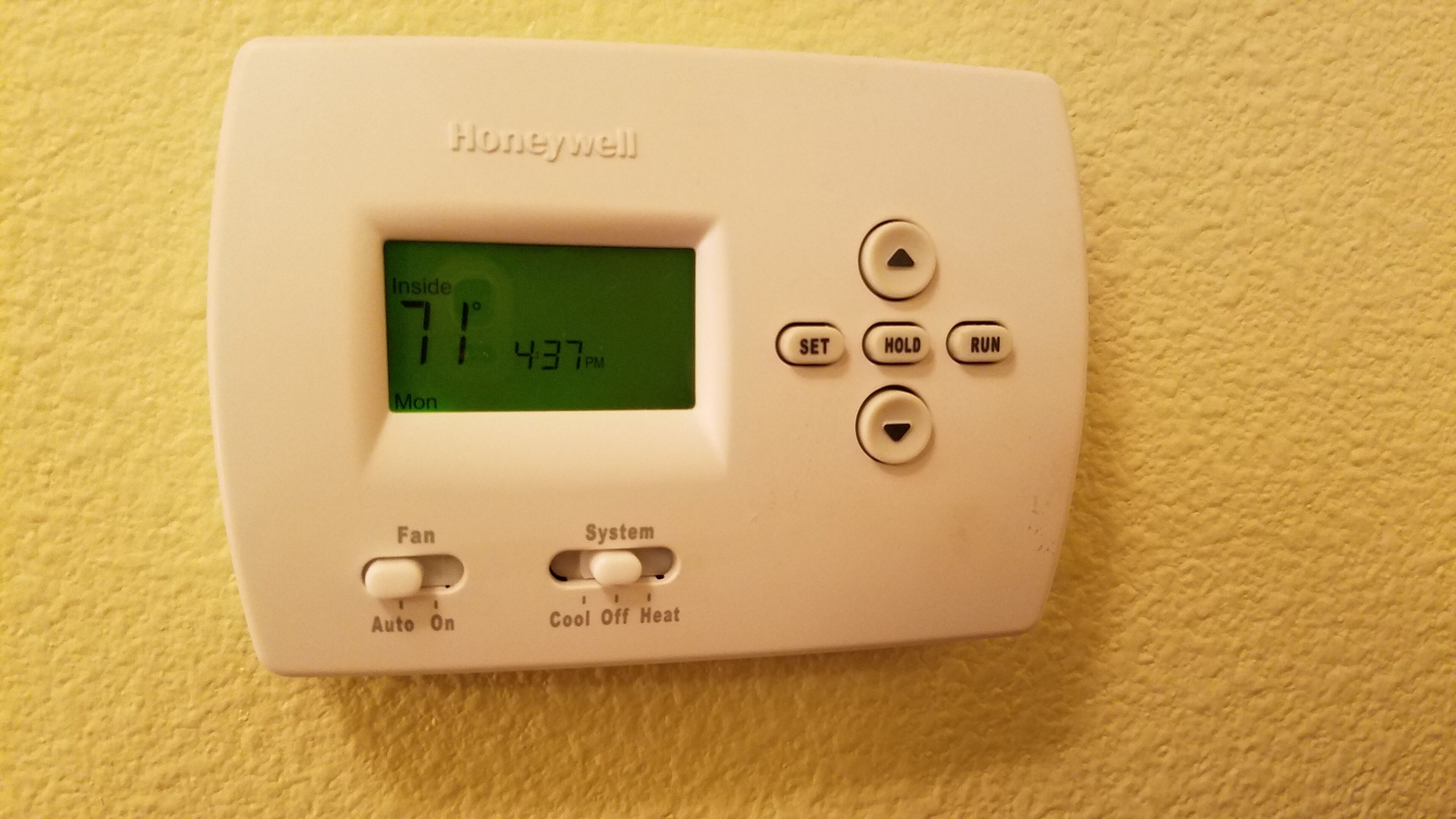 Een Honeywell thermostaat met een digitaal display dat 21 graden Celsius en 17:37 uur toont, ingesteld op AUTOMATISCH, en opties voor Ventilator en Systeem.
