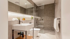 Et moderne badeværelse med vask, toilet og bruser.