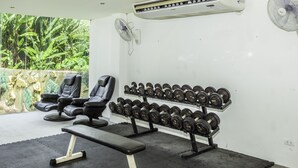 Un gimnasio con equipo de ejercicio, que incluye una banca, mancuernas y una silla de masaje.