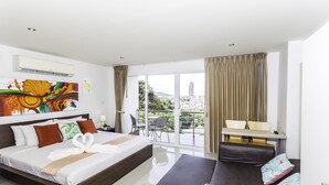 Una habitación de hotel moderna con una cama grande, un sofá, un balcón con vistas y un comedor.