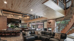 A spacious living area with a large leather sectional sofa, a kitchen with a stone fireplace, and a staircase leading to an upper level. - Zion Red Rock Oasis. (Rockville)