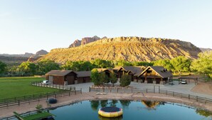 A rustic lodge with multiple cabins, a swimming pool, and a view of a mountain range. - Zion Red Rock Oasis. (Rockville)
