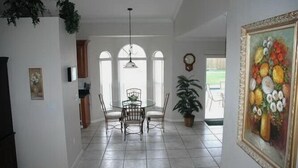 A dining area with a round table and chairs, a potted plant, and a painting on the wall. - 4 BR/3 BA Villa, Private Pool - Near Chabad & Anshei (Boynton Beach)