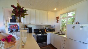 A kitchen with white cabinets, a stove, microwave, and refrigerator.