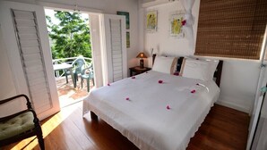 A bedroom with a large bed, a nightstand, a lamp, and a window with a curtain.