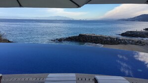 A pool with a view of the sea and distant mountains.