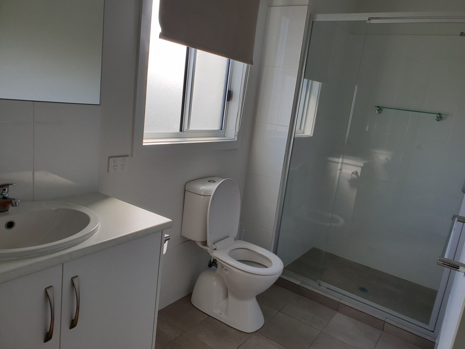 Une salle de bain équipée de toilettes, d’un lavabo et d’une douche à parois en verre.