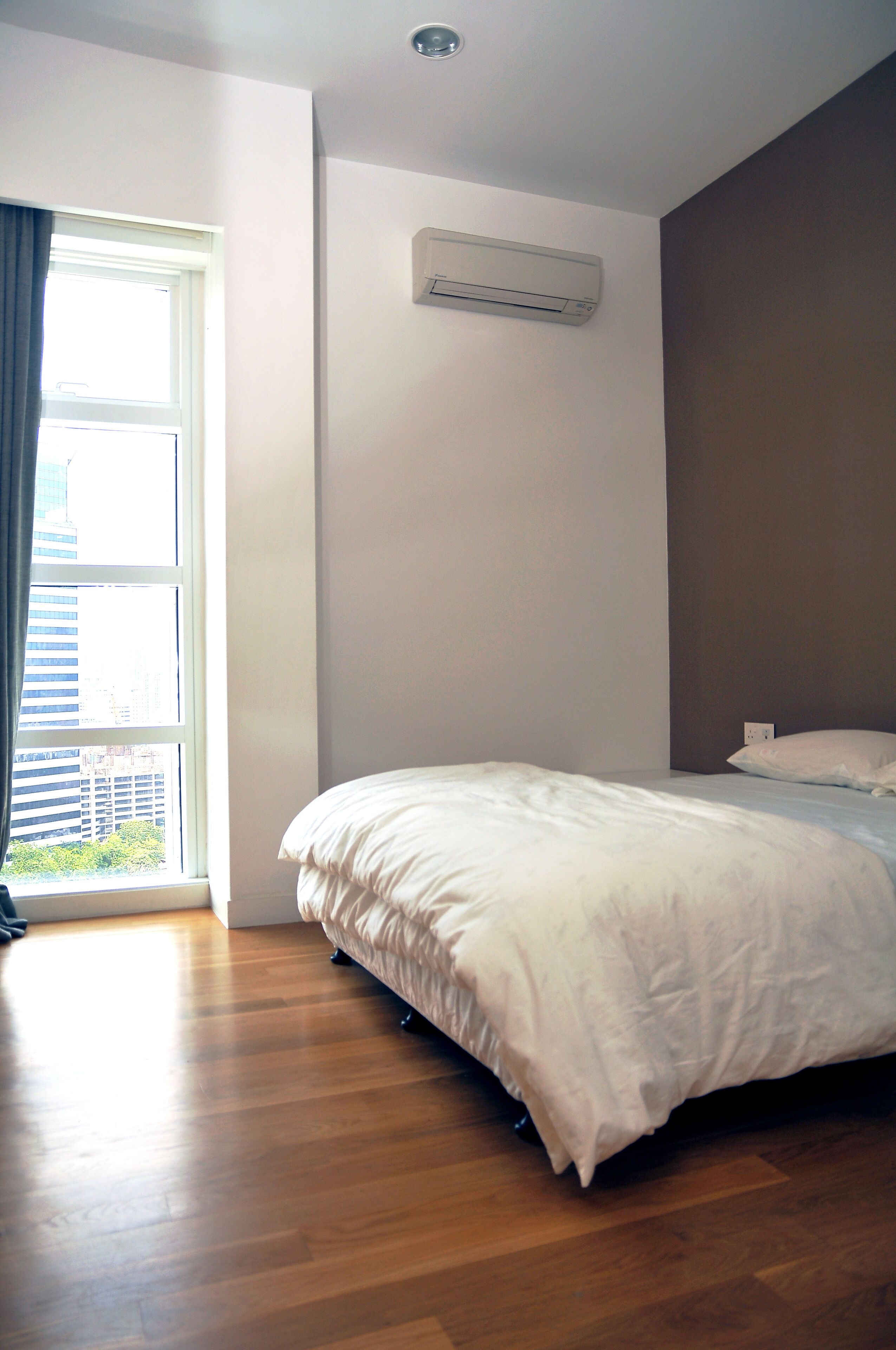 Une chambre avec un grand lit, une fenêtre avec des rideaux et un appareil de climatisation fixé au mur.