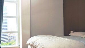 Ein Schlafzimmer mit einem großen Bett, einem Fenster mit Vorhängen und einer Klimaanlage an der Wand.