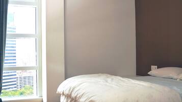 Une chambre avec un grand lit, une fenêtre avec des rideaux et un appareil de climatisation fixé au mur.