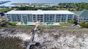 Un hotel gran amb múltiples balcons, una piscina i zona d'accés a la platja.
