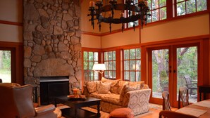 Una sala de estar acogedora con chimenea de piedra, asientos cómodos y ventanas amplias que ofrecen vistas al exterior.