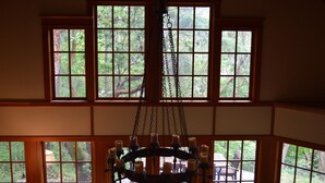 Una habitación con ventanas amplias, un candelabro y una terraza de madera visible a través de las ventanas.