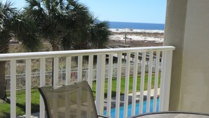 A balcony with a pool, a chair, and a table. - Inn at Dauphin Island 203 Beautifully Furnished with Great Views!! (Dauphin Island)