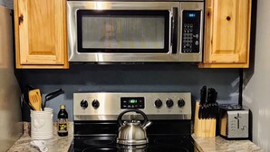 Una cocina con armarios de madera, estufa de acero inoxidable, microondas y tostadora.