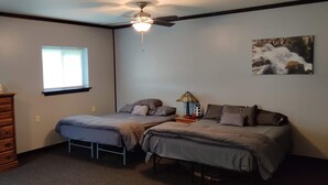 Un dormitorio con dos camas, un aparador, una ventana y dos cuadros colgados en la pared.