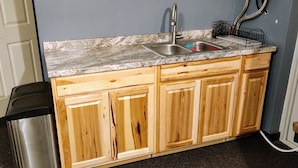 Una cocina con armarios de madera, encimera de granito, pileta de acero inoxidable y un bote de basura.