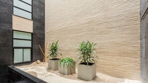 Un interior moderno con pared de ladrillo, tres plantas en macetas y suelo texturizado.