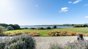 Een kustlandschap met een grasveld, lavendelstruiken en uitzicht op zee.