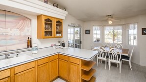 Een moderne keuken met houten kastjes, een centraal eiland en een eethoek met witte stoelen.