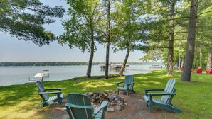 Un espace de détente aménagé au bord du lac, avec des fauteuils Adirondack et un foyer.