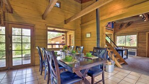 Un comedor de madera con una mesa preparada para seis personas, sillas y vistas al exterior.