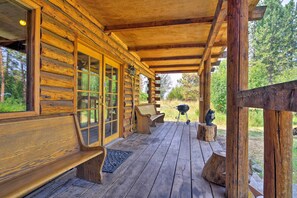 Une cabane en bois avec une véranda, des bancs en bois et un barbecue.