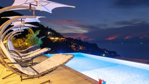 An infinity pool with lounge chairs and a canopy, surrounded by a mountainous landscape. - The  new luxury architect modern villa in  Haad Yao  with huge amazing seaview. (Ko Pha Ngan)