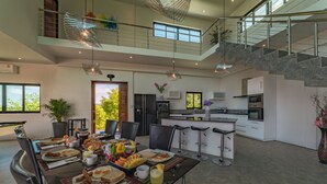 A spacious modern kitchen with a dining area, a staircase, and large windows. - The  new luxury architect modern villa in  Haad Yao  with huge amazing seaview. (Ko Pha Ngan)