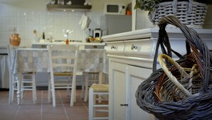 Et køkken med hvide skabe, en mikrobølgeovn og en kurv hængende på væggen.