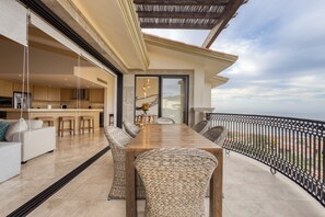 A spacious balcony with a dining table and chairs, overlooking a scenic view.