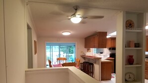 Una cocina con armarios de madera, un ventilador de techo y una zona de comedor con sillas y una mesa.