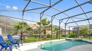 A pool area with a glass enclosure, blue chairs, and palm trees.