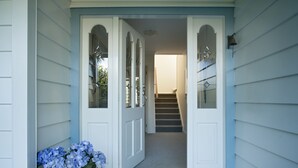 A house entrance with a front door, a staircase leading to the upper floor, and a flower arrangement on the left. - Escape North - Extended Family Retreat, located in central Russell (Russell)