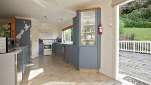 A modern kitchen with blue cabinets, a white refrigerator, and a view of a garden through a sliding glass door. - Escape North - Extended Family Retreat, located in central Russell (Russell)