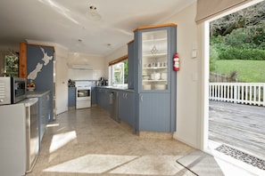 A modern kitchen with blue cabinets, a white refrigerator, and a view of a garden through a sliding glass door. - Escape North - Extended Family Retreat, located in central Russell (Russell)