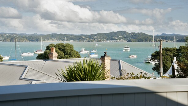 A coastal view with boats on the water, a mountain range in the background, and a building with a roof in the foreground. - Escape North - Extended Family Retreat, located in central Russell (Russell)