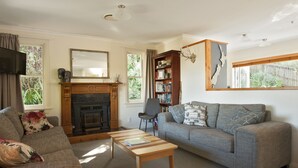 A living room with a fireplace, a sofa, a coffee table, and a bookshelf. - Escape North - Extended Family Retreat, located in central Russell (Russell)
