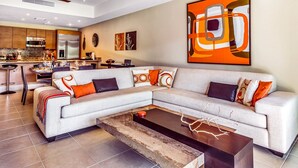 A modern living room with a sectional sofa, a coffee table, and a kitchen in the background. - veElegant Villa, Pool, Golf Cart, Beach & Resort Amenities. Secure & Relaxing (Río Grande)