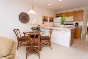 A modern kitchen with wooden cabinets, a central island, and a dining area with wicker chairs.