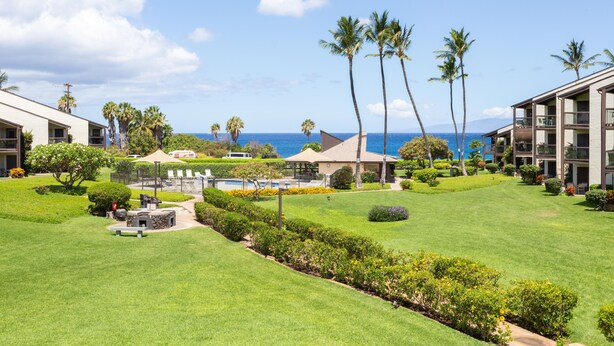 A resort with a well-maintained lawn, palm trees, and a view of the ocean. - Hale Kamaole 141 Ground floor condo, easy access to best beach on Maui! (Kihei)