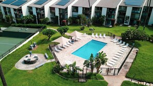 A rooftop pool surrounded by lounge chairs and a tennis court. - Hale Kamaole 141 Ground floor condo, easy access to best beach on Maui! (Kihei)