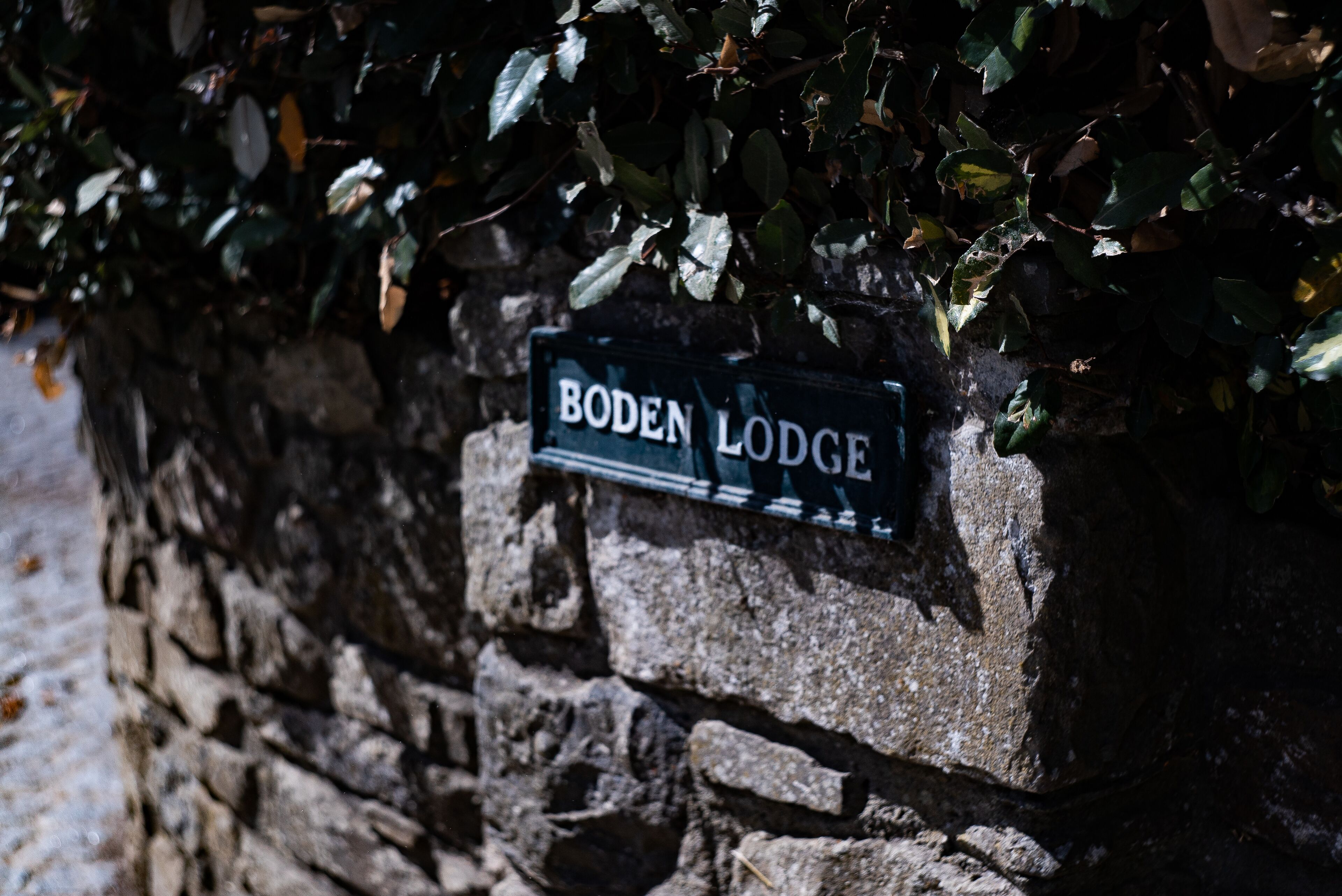 A stone wall with a sign that reads "Boden Lodge."