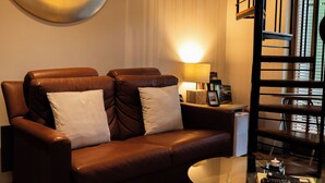 A brown leather sofa with two pillows, a small table with a lamp, and a bookshelf with books. - The Lodge at Bodenlodge is located in the charming Costal Village of Malahide (Malahide)