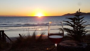 Ein Glas Rotwein auf einem Tisch mit Blick auf das Meer und einen Sonnenuntergang.