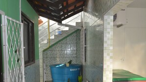 Un corridoio stretto con pareti piastrellate, una vasca da bagno blu, un cestino e una pianta in vaso.