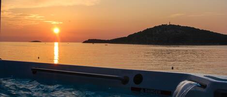 A sunset view from a boat with a "DANGER" sign, calm water, and a distant island.
