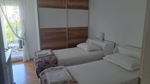 A hotel room with two beds, a wooden headboard, a bedside table with a lamp, and a view of the outdoors through a window. - Apartman MAJDA with balkony (Split)