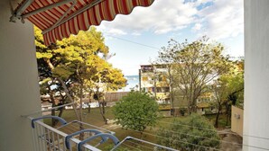A balcony with a striped awning overlooking a residential area with trees and buildings. - Apartman MAJDA with balkony (Split)