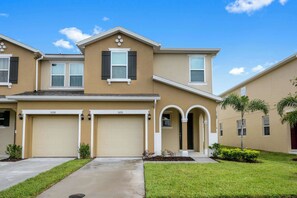 A two-story residential building with two garages, a front entrance with an archway, and a well-maintained lawn. - Modern Villa, Prime Location! 4Bds Townhouse 5126 (Kissimee)